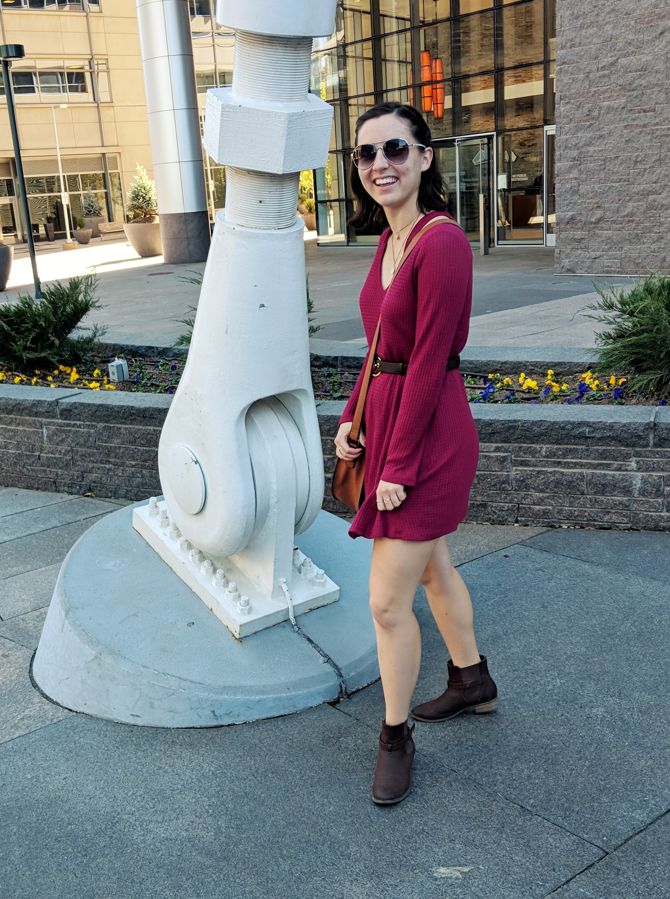a girl twirling in a red dress with brown booties and aviator sunglasses
