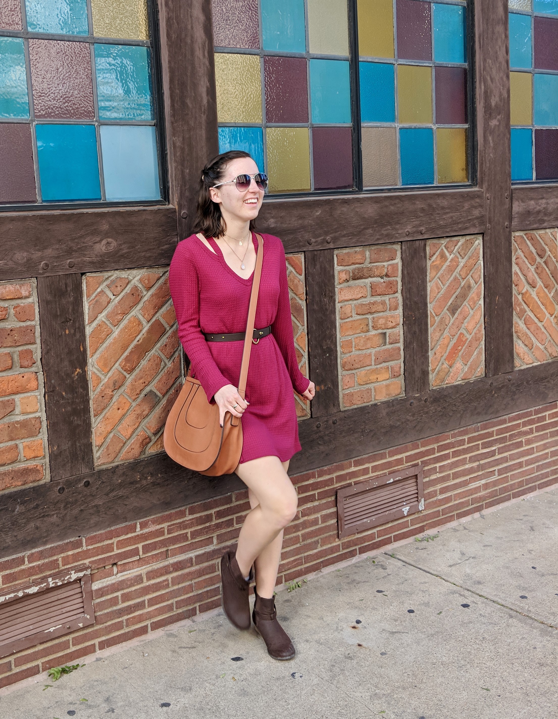 fashionista in a red dress leaning against a brick wall