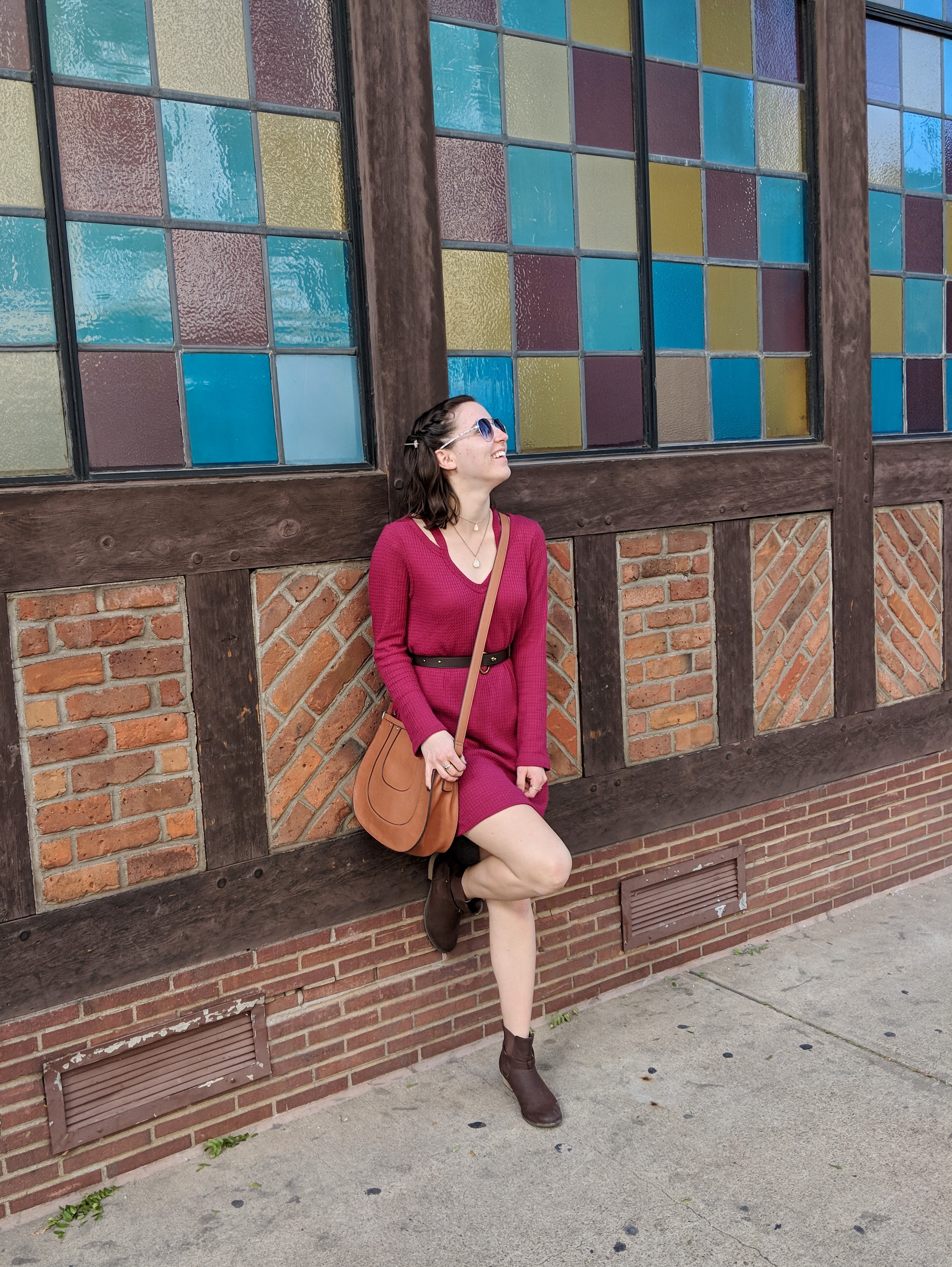 girl in a red dress leaning against a colorful wall