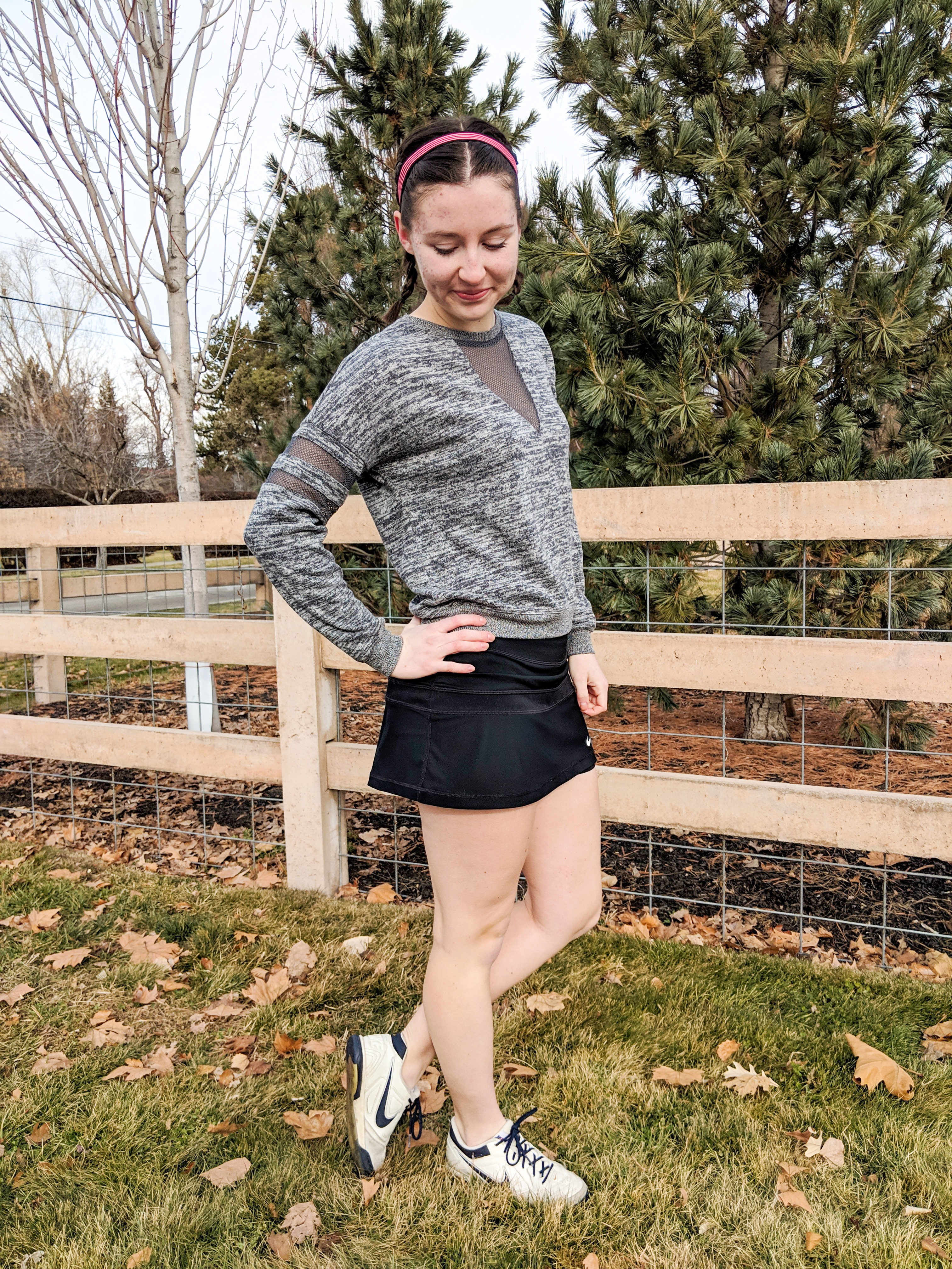 grey sweatshirt, black tennis skirt, white tennis shoes