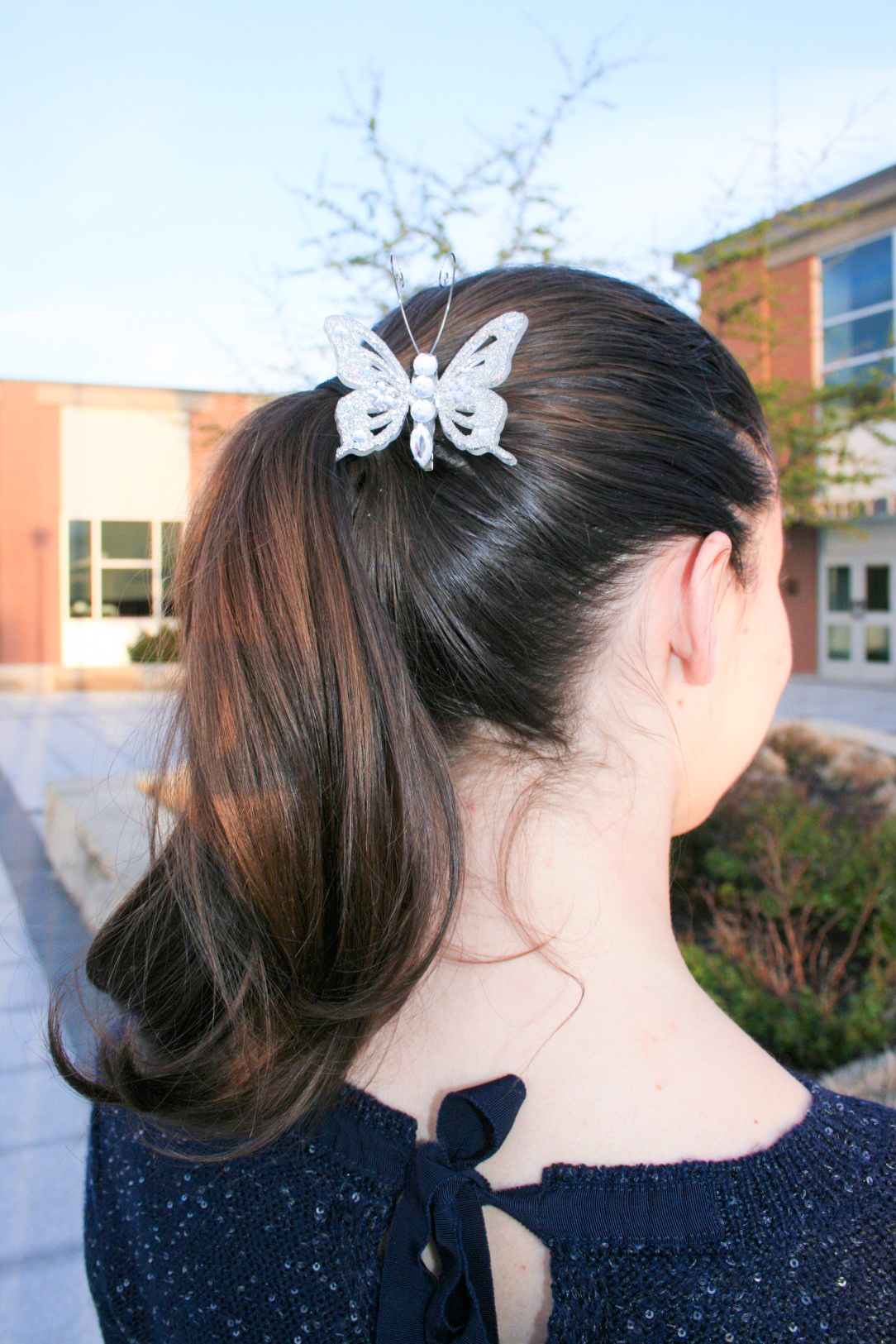 curly pony tail, butterfly hair clip, navy sweater