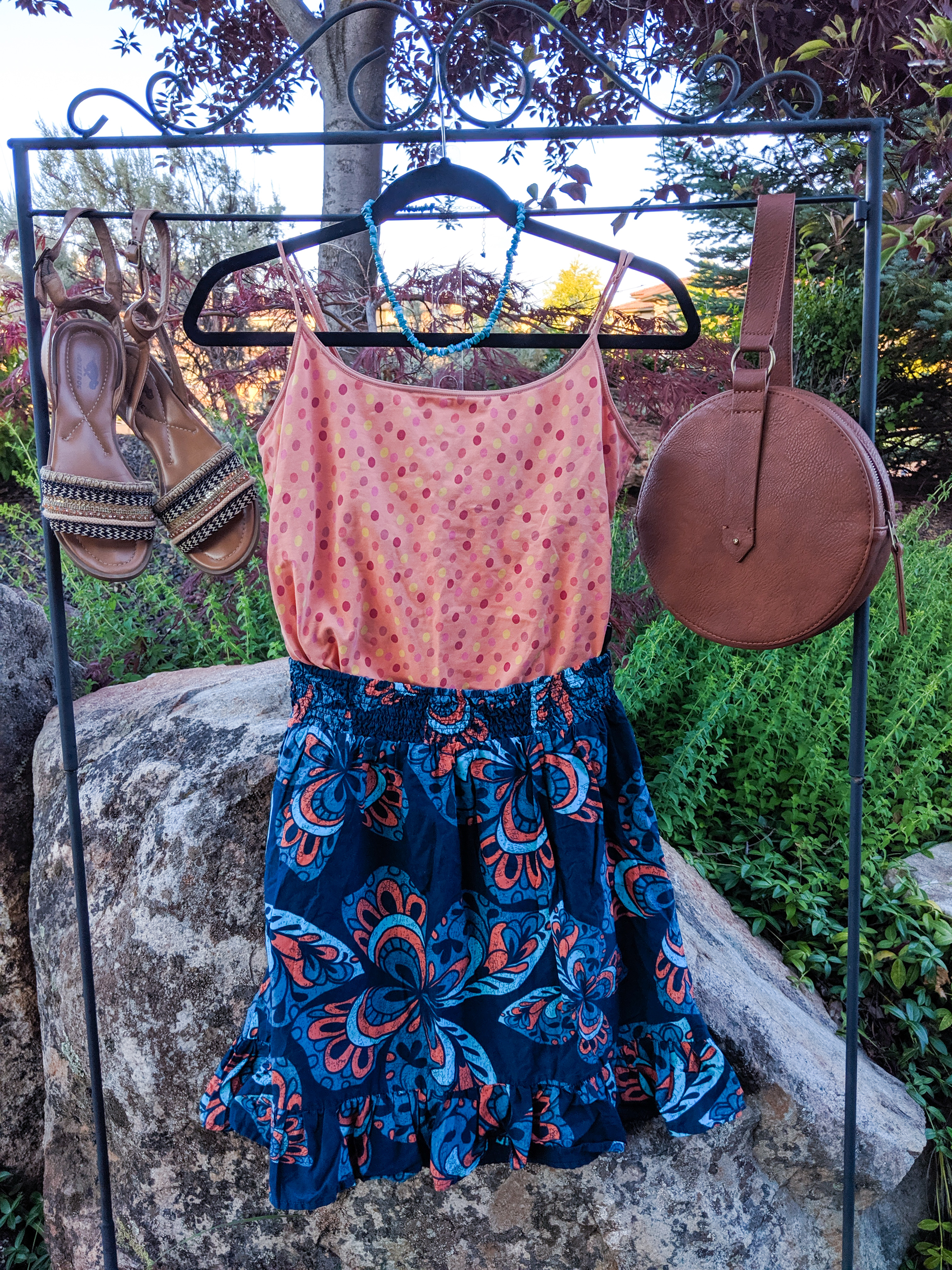 orange polka dot top, blue patterned skirt, brown accessories