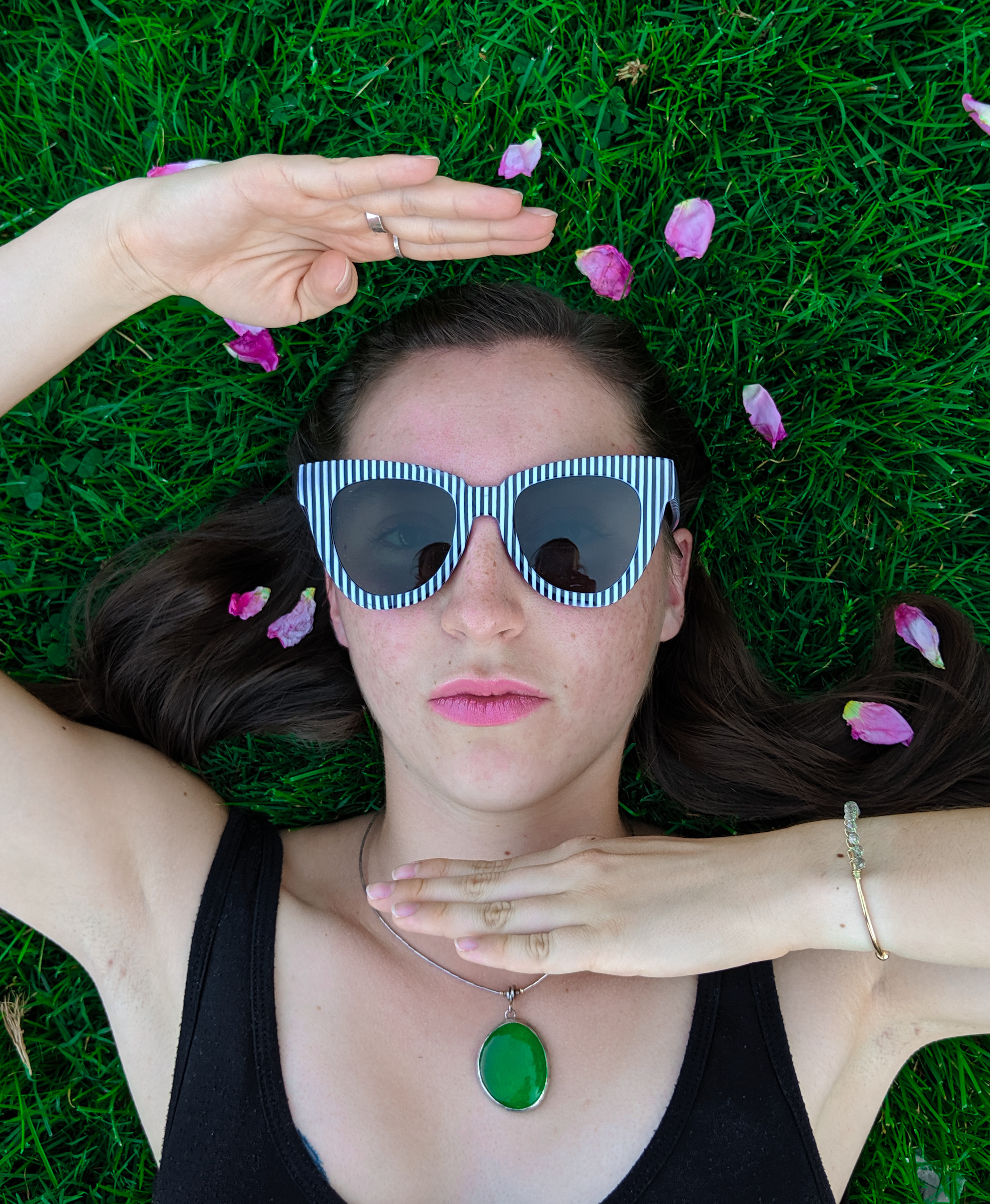 rose petals, black dress, green necklace, striped sunglasses