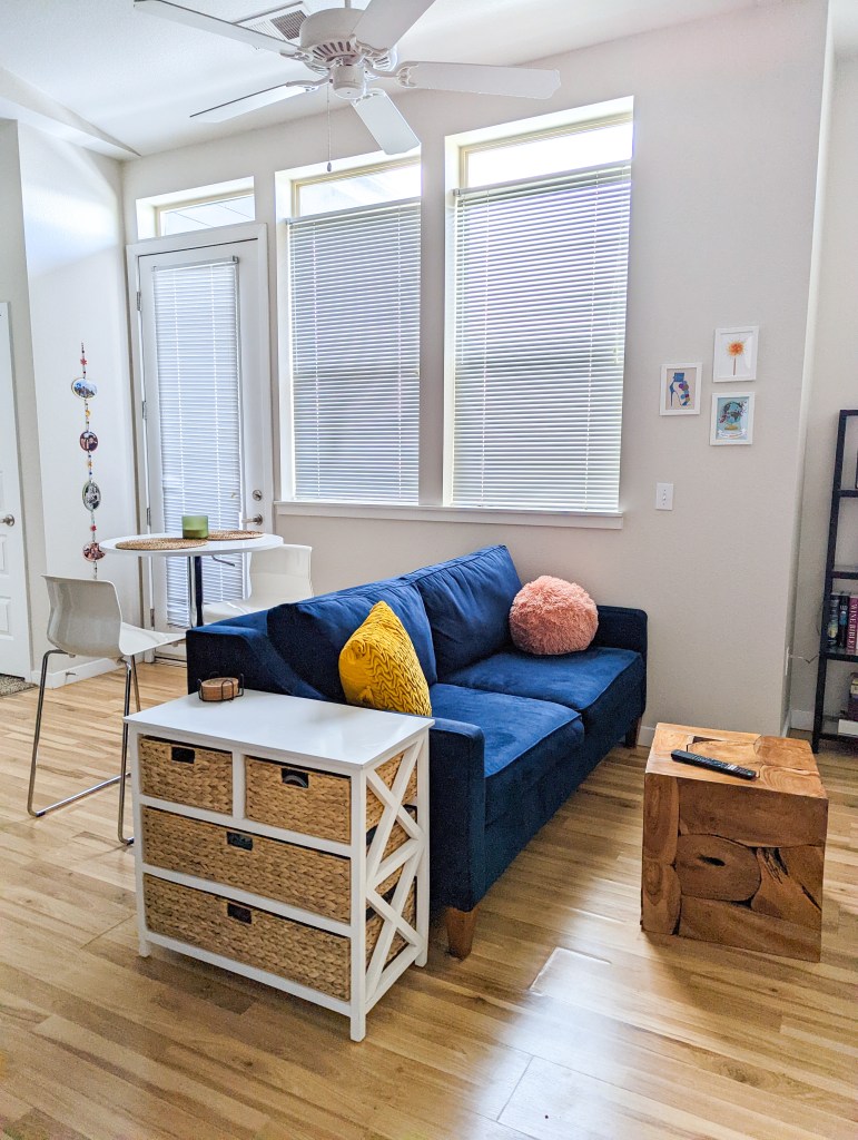 navy-couch-mustard-throw-pillow-rattan-drawers-wooden-cube