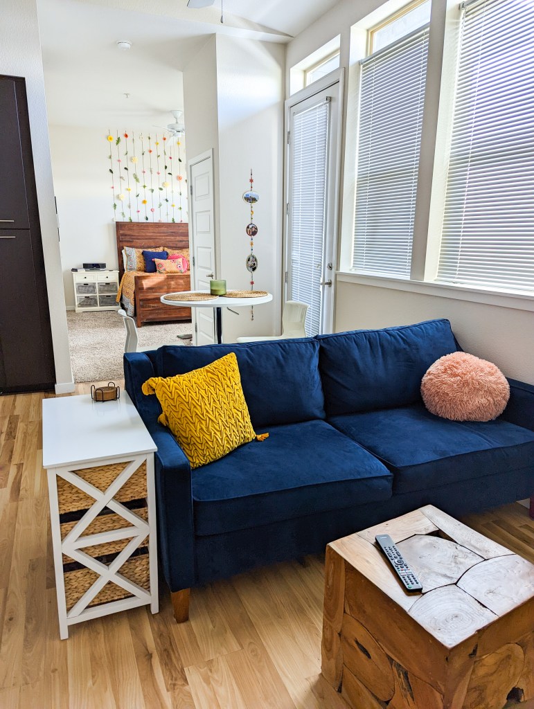 post-grad-apartment-blue-couch-mustard-throw-pillow-blush-pillow-wooden-coffee-table