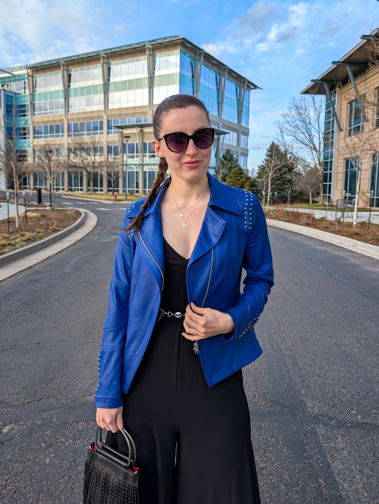 cobalt blue moto jacket black jumpsuit silver chain belt sunglasses