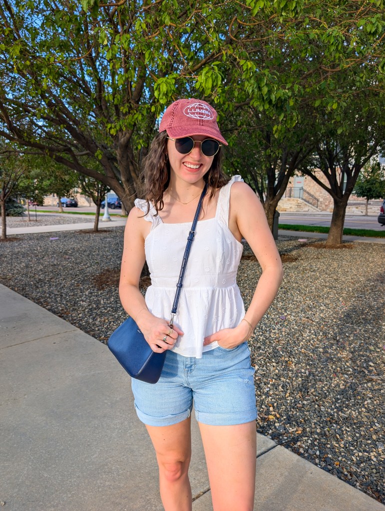 hand-me-downs white peplum top red Lumon hat Severance light wash denim shorts navy purse